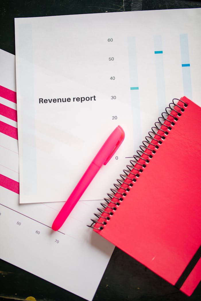 Revenue report with a pink notebook and pen on a bright flatlay, perfect for business presentations.